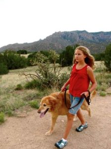 girl walking with with dog on trail